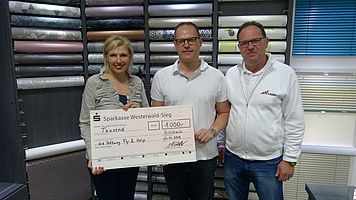 Uwe und Markus Weller übergeben den Spendenscheck an Pia Schmitz-Formes von FLY & HELP
