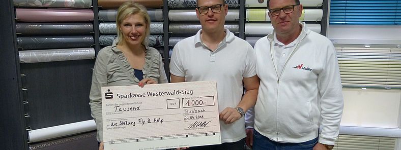 Uwe und Markus Weller übergeben den Spendenscheck an Pia Schmitz-Formes von FLY & HELP